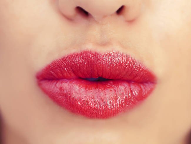 Frau hat volle rote Lippen dank Lip enhancer