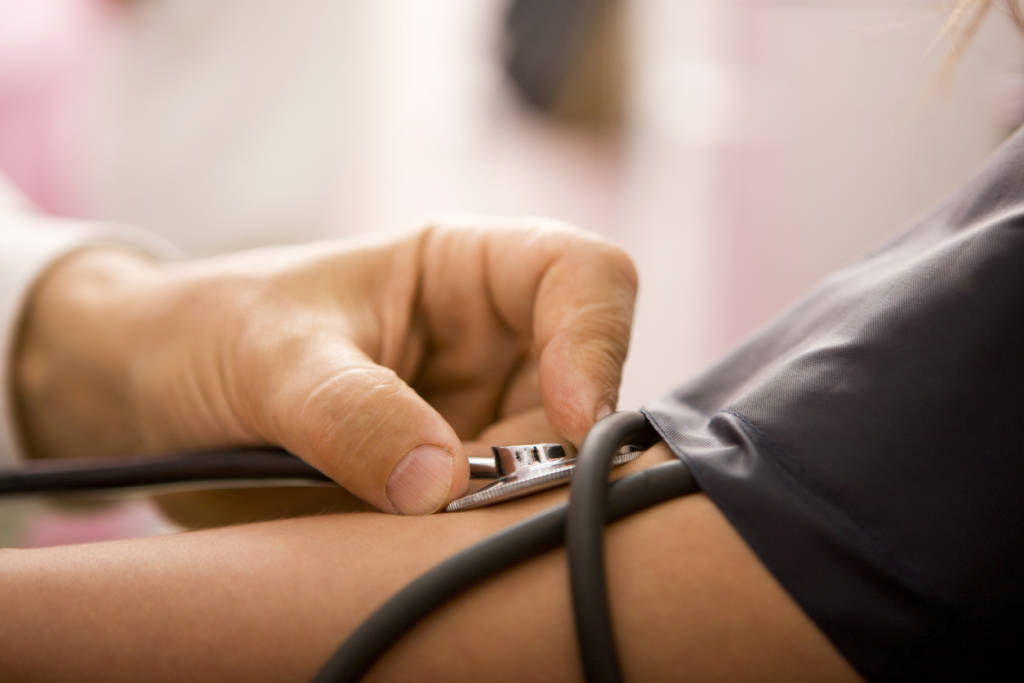 Arzt misst bei Patient Blutdruck im Rahmen der Gesundenuntersuchung